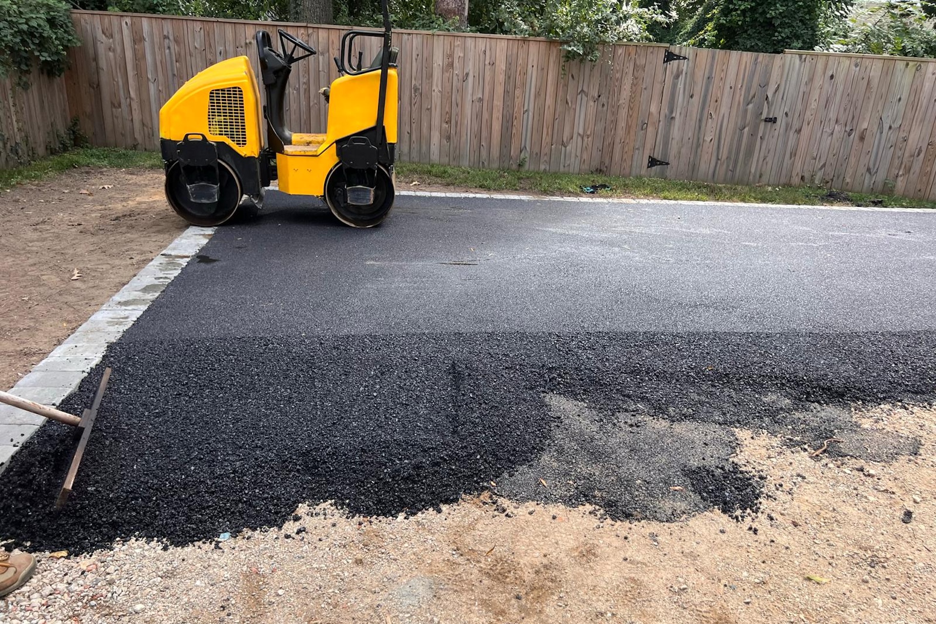 Asphalt equipment working on a residential driveway.